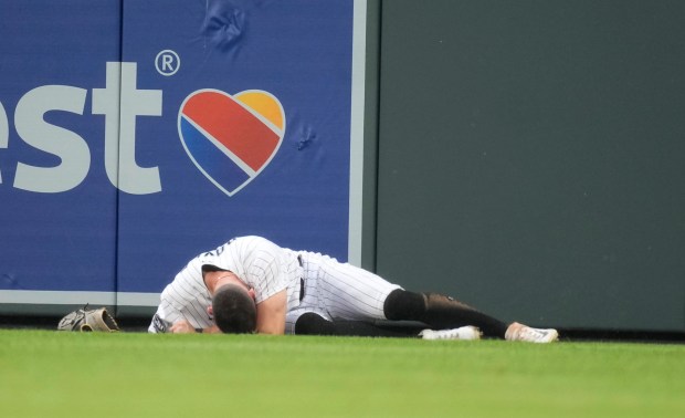 Colorado Rockies center fielder Brenton Doyle lies at the warning track after running into the wall while pursuing a home run by Miami Marlins' Jorge Soler during the ninth inning of a baseball game Thursday, May 25, 2023, in Denver. (AP Photo/David Zalubowski)