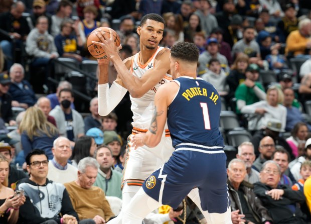 San Antonio Spurs center Victor Wembanyama, left, looks to pass the ball as Denver Nuggets forward Michael Porter Jr., right, defends in the first half of an NBA basketball game Sunday, Nov. 26, 2023, in Denver. (AP Photo/David Zalubowski)