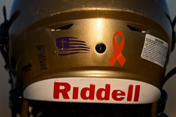 BROOMFIELD, CO - NOVEMBER 28: The entire Holy Family football team wears orange ribbons on their helmets in support of Crystal Gabriel, wife of head coach Mike Gabriel during practice at Holy Family football field before practice on November 28, 2023 in Broomfield, Colorado. Crystal Gabriel, who is married to head coach Mike Gabriel, has Acute Myeloid Leukemia and recently had a bone marrow transplant. The football team has a long family history with deep roots going back generations and over a half century at the high school. Head coach Mike D, Gabriel, his father offensive line coach Mike G. Gabriel, Sr and brother Assistant coach Mark Gabriel are all part of the coaching staff. Their kids play on the team as well. Star running back and safety Dominic Gabriel, his brother and sophomore player Nick and cousin Andrew Berens, also a sophomore all play for the team. Holy Family will be taking on Lutheran at the 3A state football championships this weekend. (Photo by Helen H. Richardson/The Denver Post)
