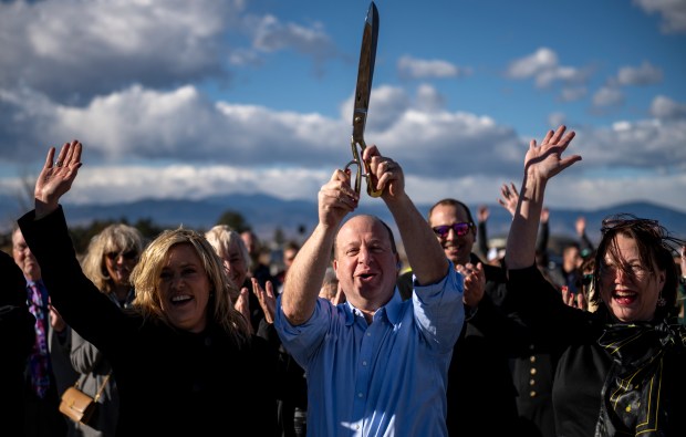 Colorado Gov. Jared Polis, center, holds his scissors high after cutting the ribbon during a ribbon-cutting ceremony for the north I-25 Express Lanes at the Kendall Parkway Park-And-Ride near I-25 between the U.S. Highway 34 and Crossroads Boulevard interchanges in Loveland Thursday, Dec. 7, 2023. CDOT announced that the I-25 Express Lanes between Berthoud and Fort Collins would open December 15 and the mobility hub at Centerra Loveland Station, which features Bustang bus stops between the northbound and southbound lanes of I-25, would begin operating in the spring of 2024. (Alex McIntyre, Special to The Denver Post)